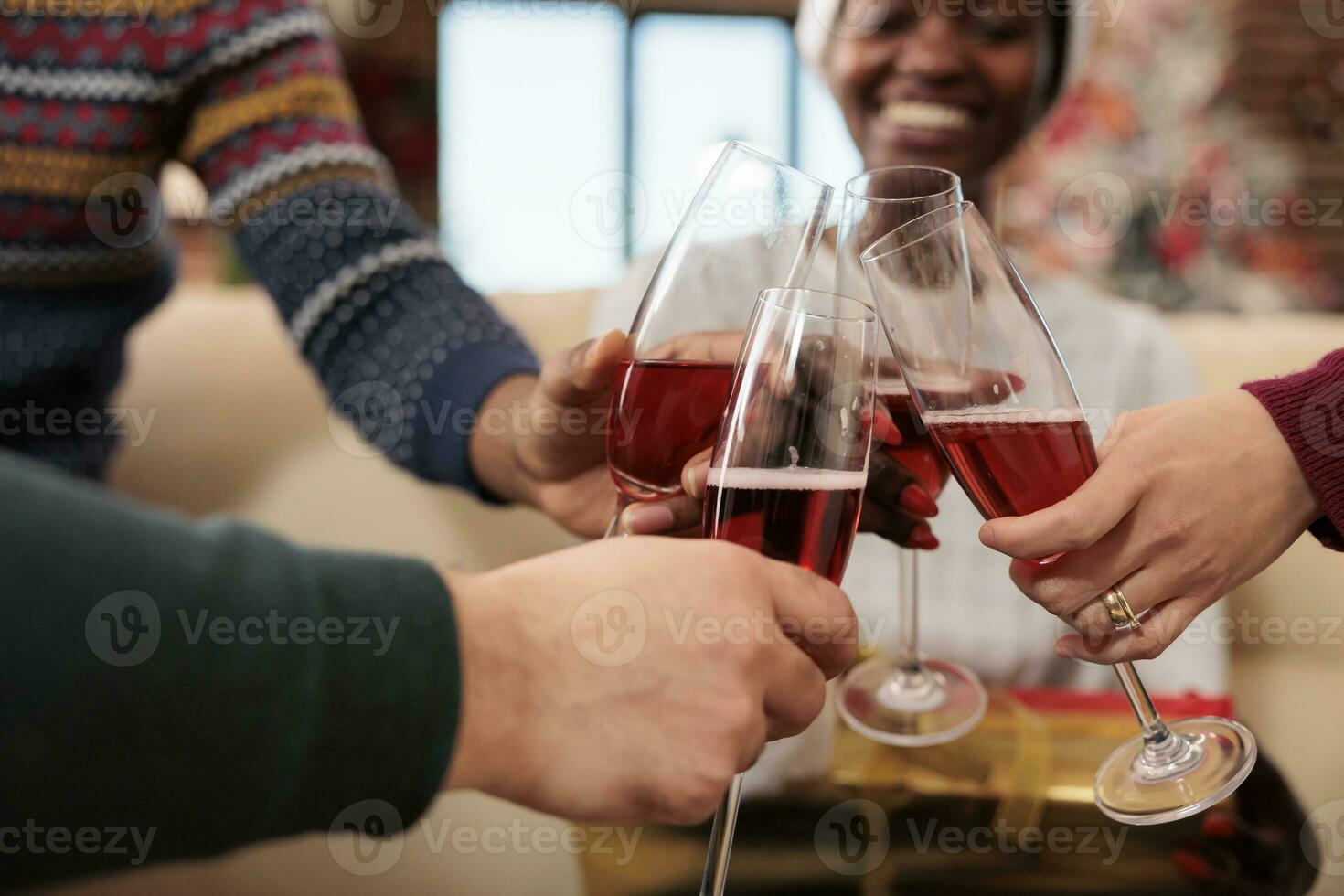 Cheerful colleagues holding beverage glasses and clinking while celebrating winter seasonal holiday together. Company workers drinking sparkling wine at christmas corporate party photo