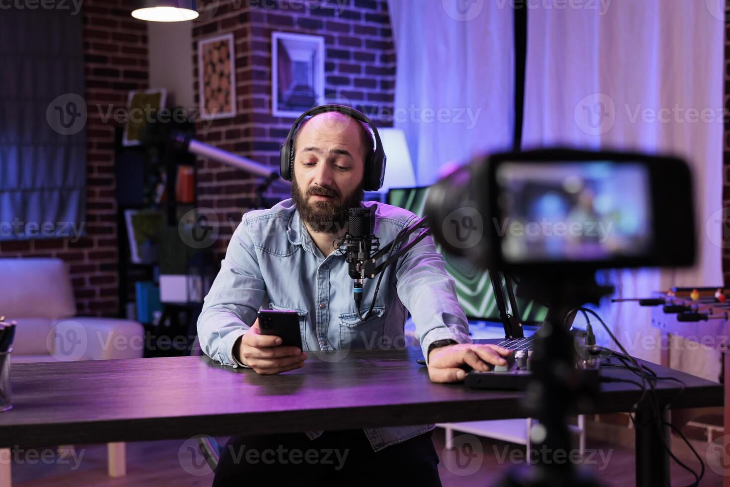 Content creator doing live broadcasting for online streaming service surprised by comments received from followers. Famous vlogger interacting with fans while recording in living room studio photo