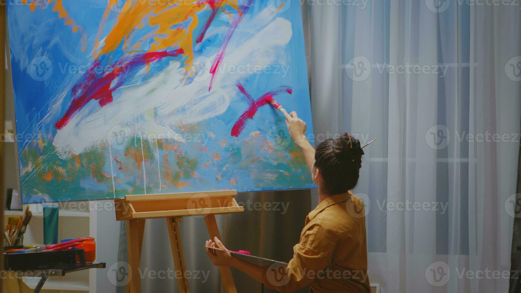 artista trabajando en su estudio pintura un lona con diferente colores. foto