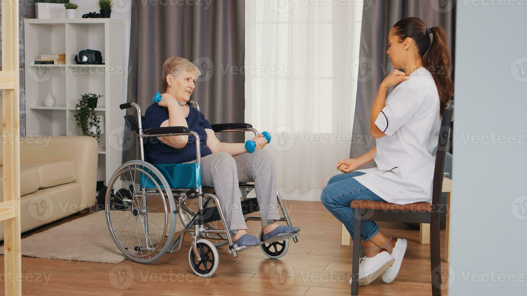 Old lady in wheelchair doing physical rehabilitation with nurse. Training, sport, recovery and lifting, old person retirement home, healthcare nursing, health support, social assistance, doctor and home service photo