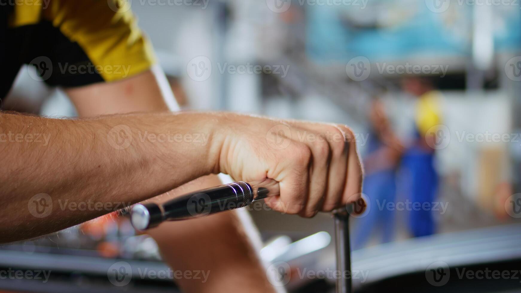 Qualified serviceman in car service picks torque wrench from work station bench, using it to tighten bolts after replacing engine. Garage worker fixes client automobile, jib down shot photo