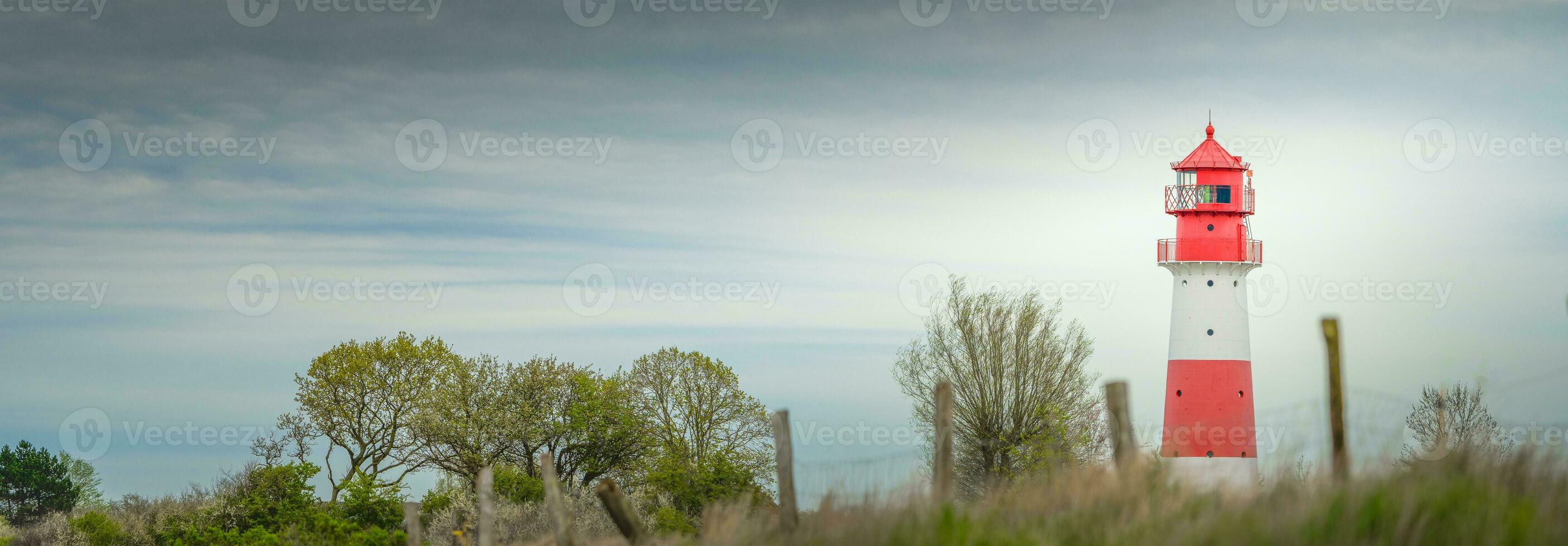 Panorama of a lighthouse on a dyke in cloudy weather photo