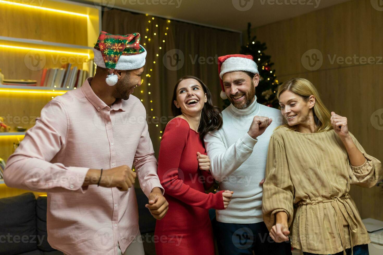 cuatro amigos celebrando bailando en Navidad cerca Navidad árbol a hogar, diverso grupo de invitados a casa fiesta teniendo divertida. foto