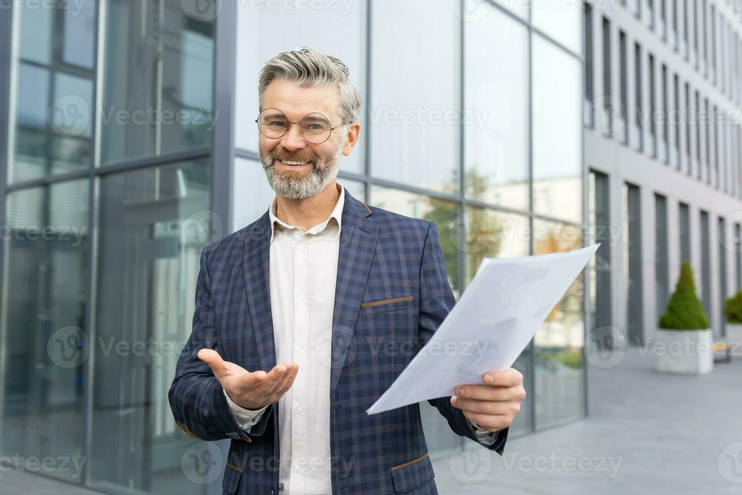 retrato maduro exitoso gris peludo empresario financiero fuera de oficina edificio, jefe participación estadístico informes en manos, alegre sonriente y mirando a cámara, satisfecho logro resultados. foto