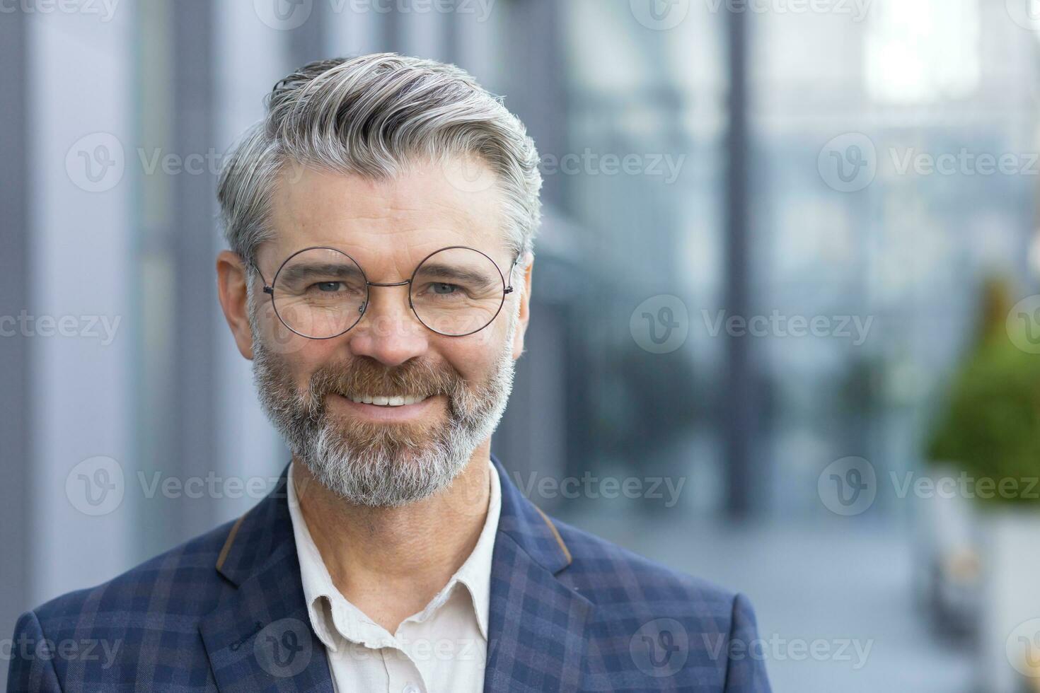 Successful gray haired man in business suit close up, portrait of mature businessman with beard and glasses, banker investor smiling and looking at camera from outside office building boss satisfied. photo