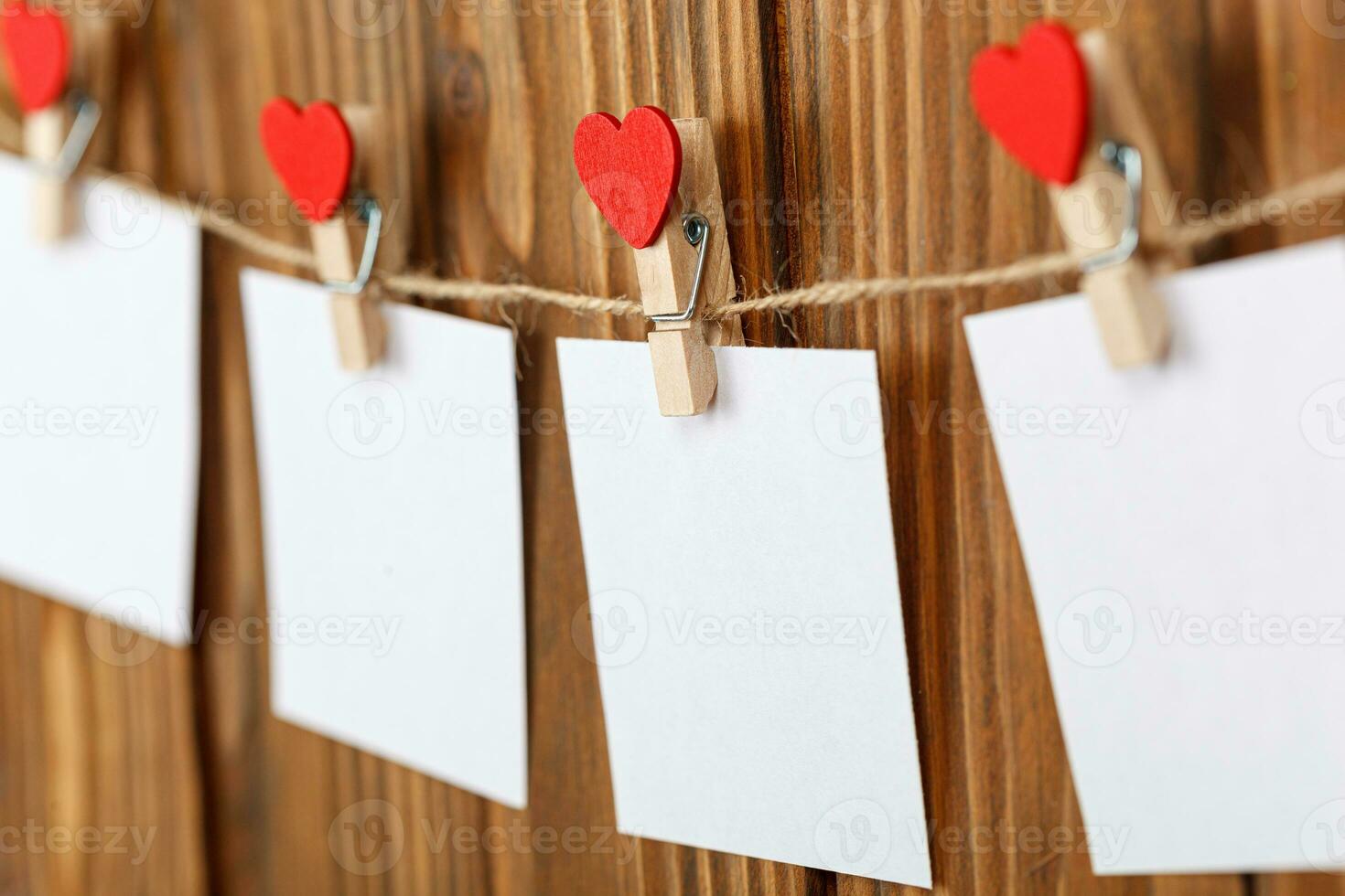 white pieces of paper on clothespins with a heart on a wooden background photo