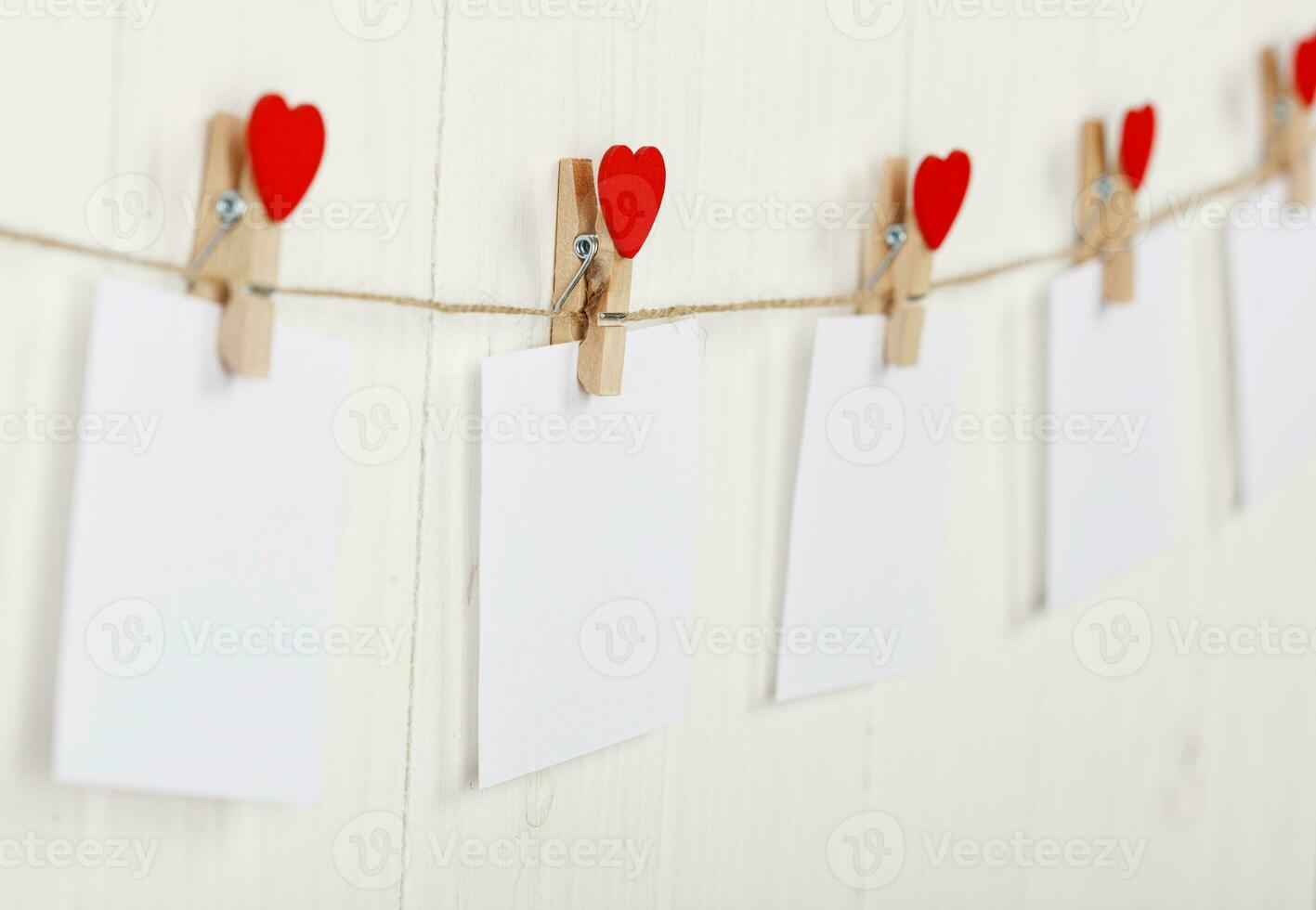 white pieces of paper on clothespins with a heart on a wooden background photo