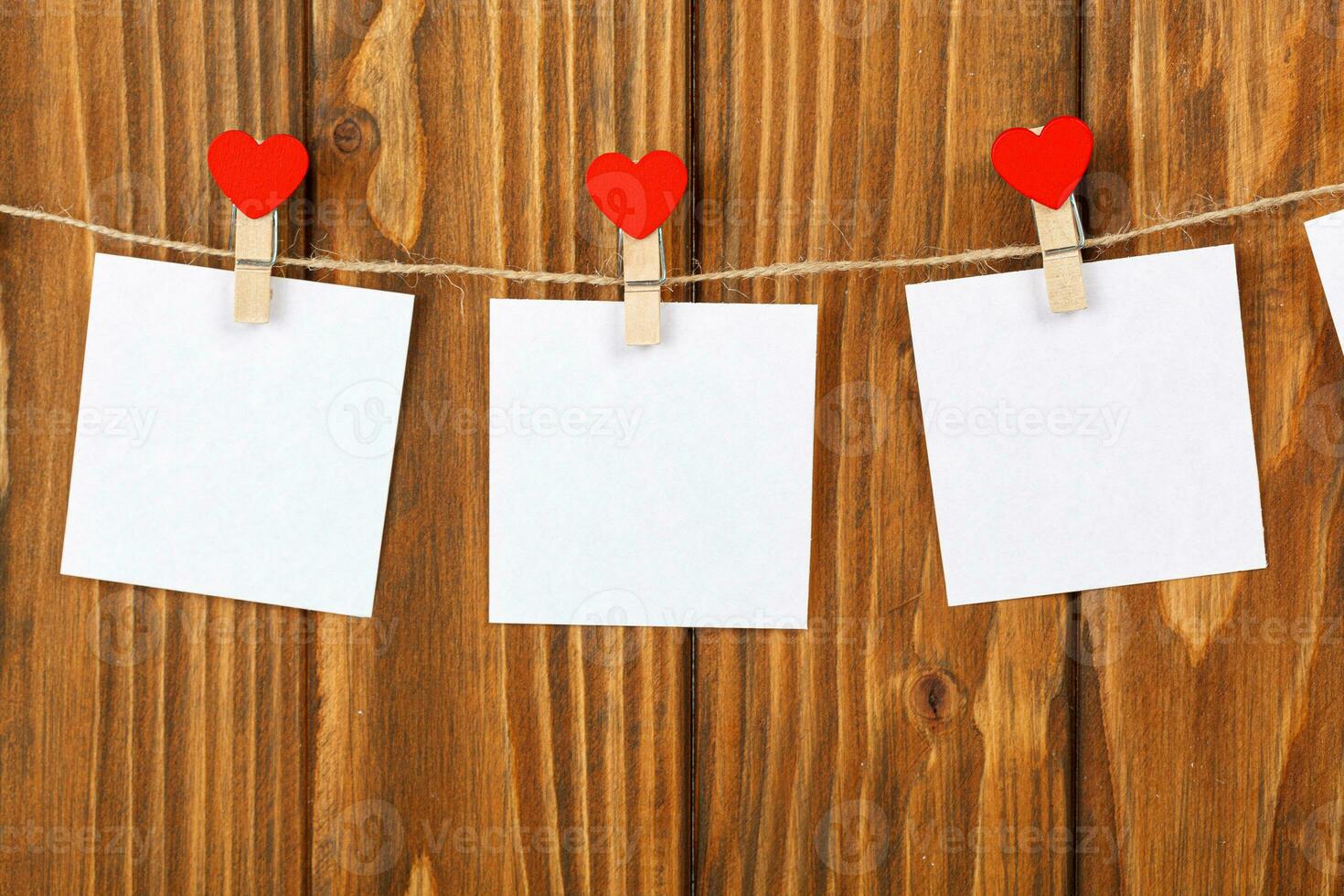 white pieces of paper on clothespins with a heart on a wooden background photo