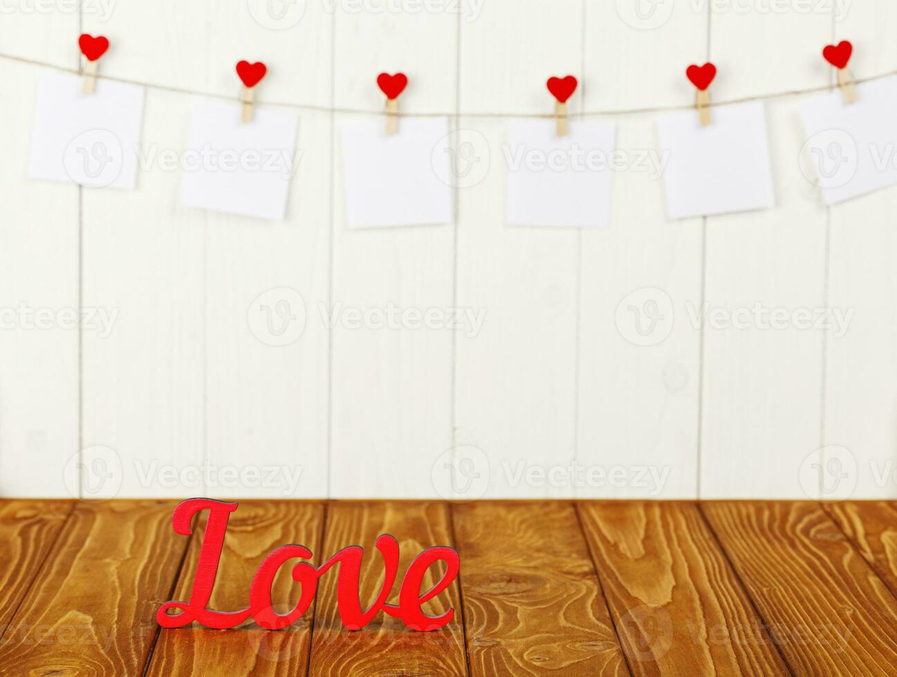 white pieces of paper on clothespins with a heart on a wooden background, a wooden inscription I love you photo