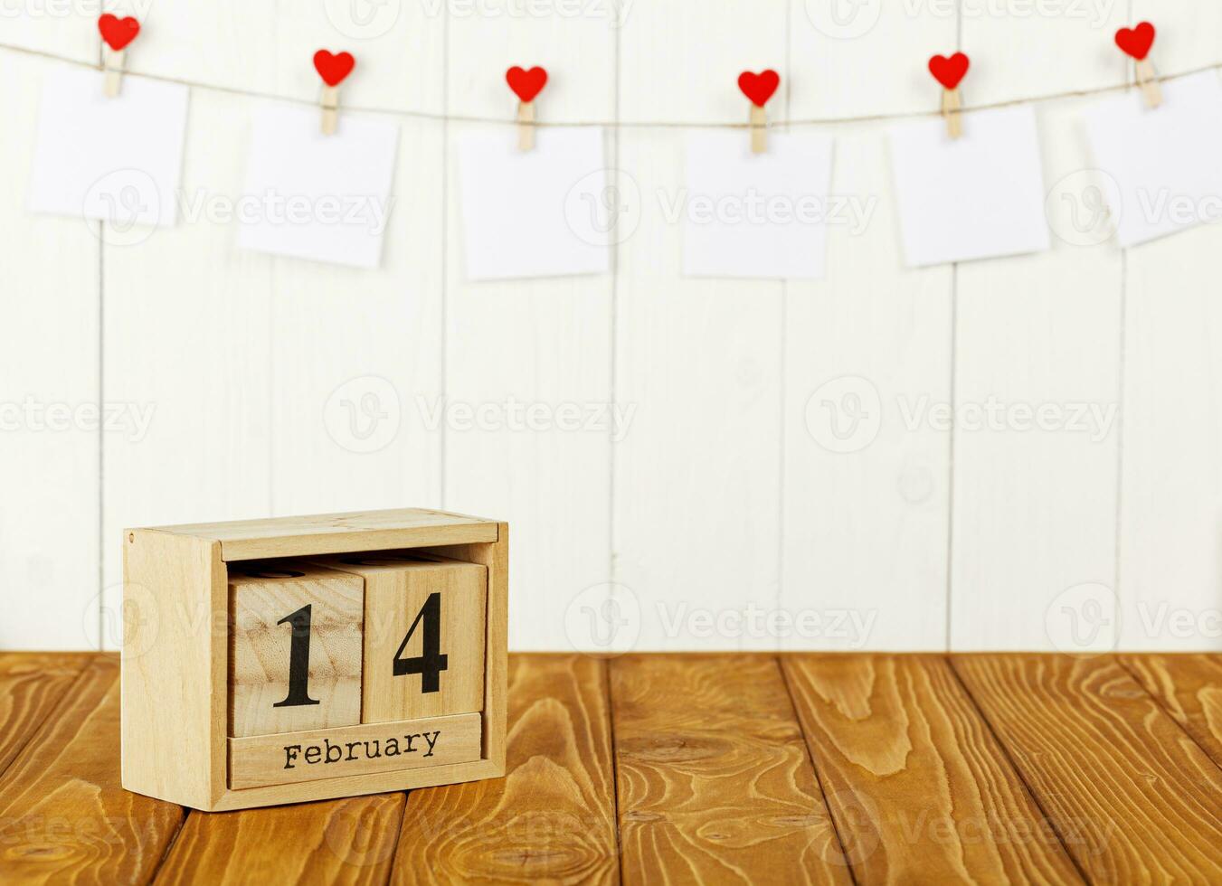 blanco piezas de papel en pinzas para la ropa con un corazón en un de madera fondo, calendario febrero 14 foto