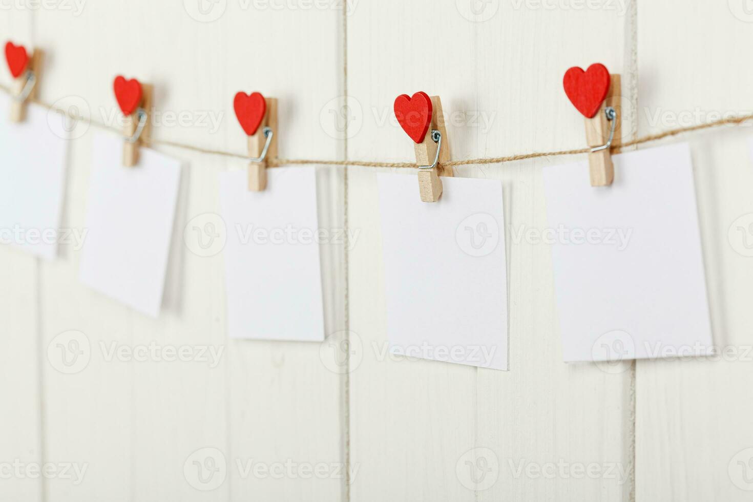 white pieces of paper on clothespins with a heart on a wooden background photo