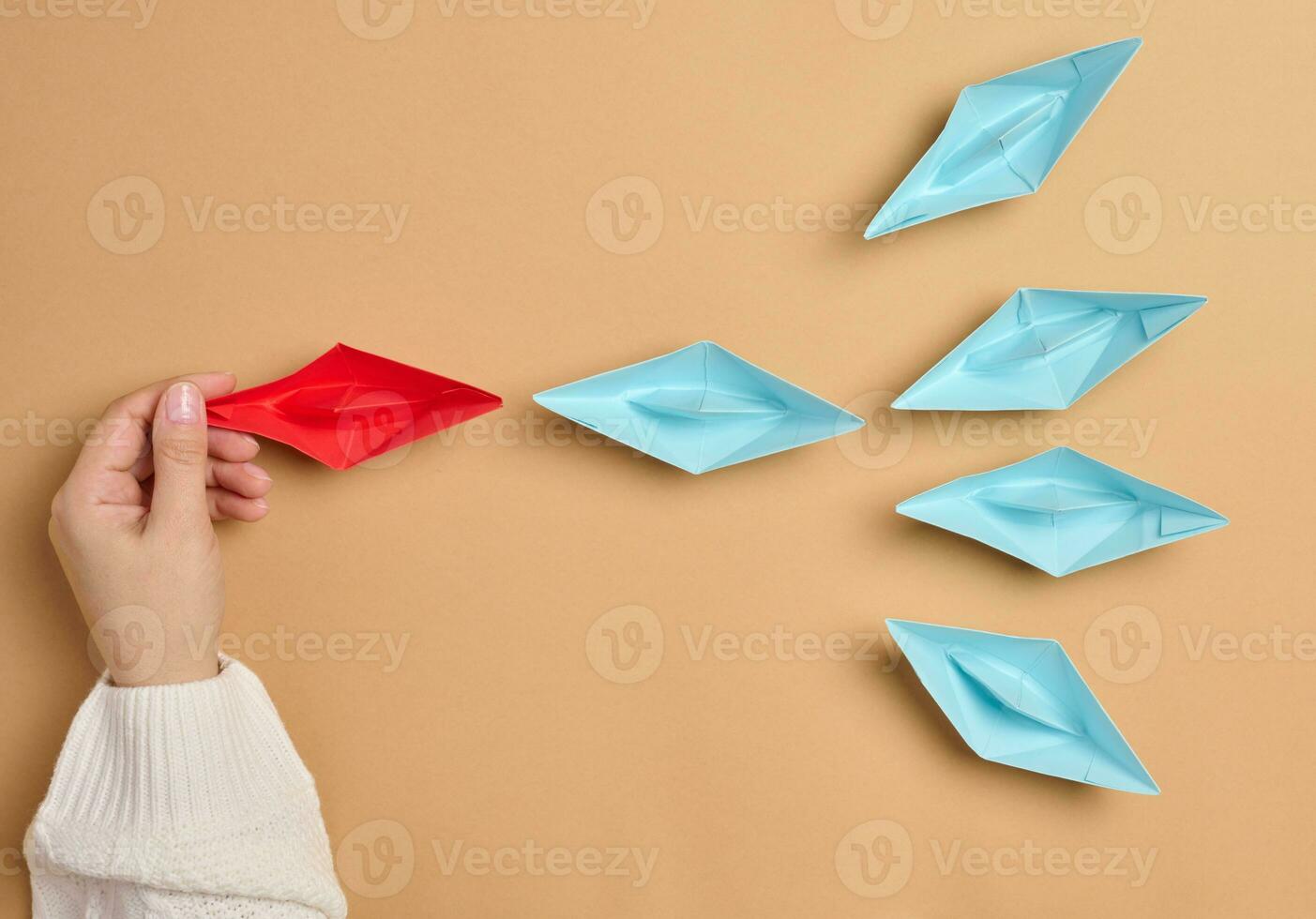 Group of paper boats on a brown background.Concept of a strong leader in a team, manipulation of the masses photo