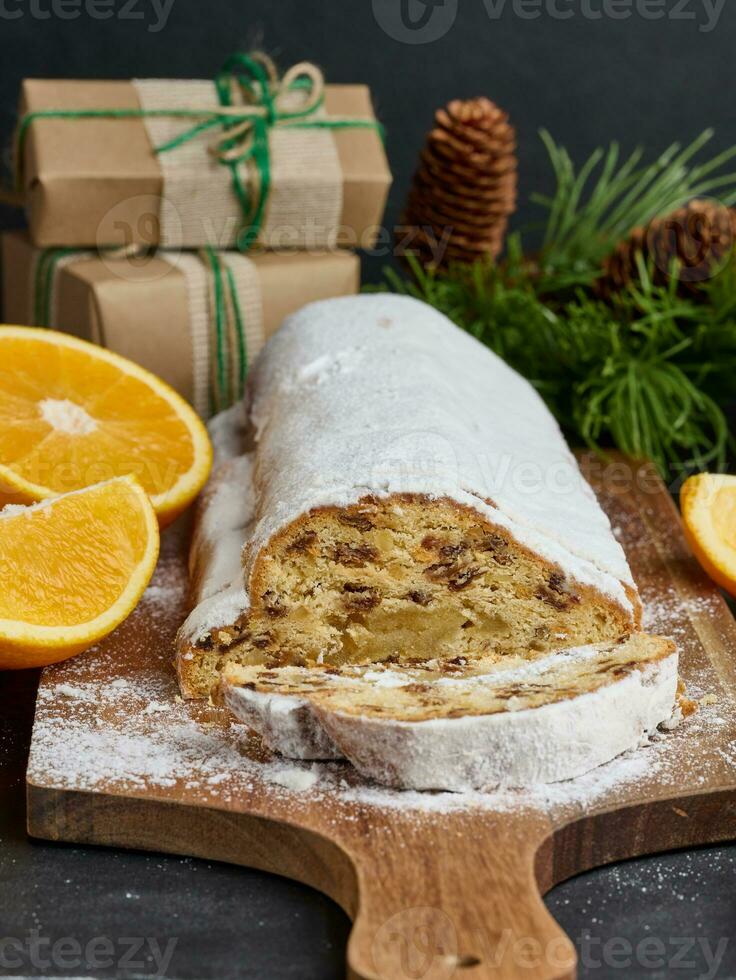 Christmas pastries stollen sprinkled with powdered sugar on the table, festive dessert photo