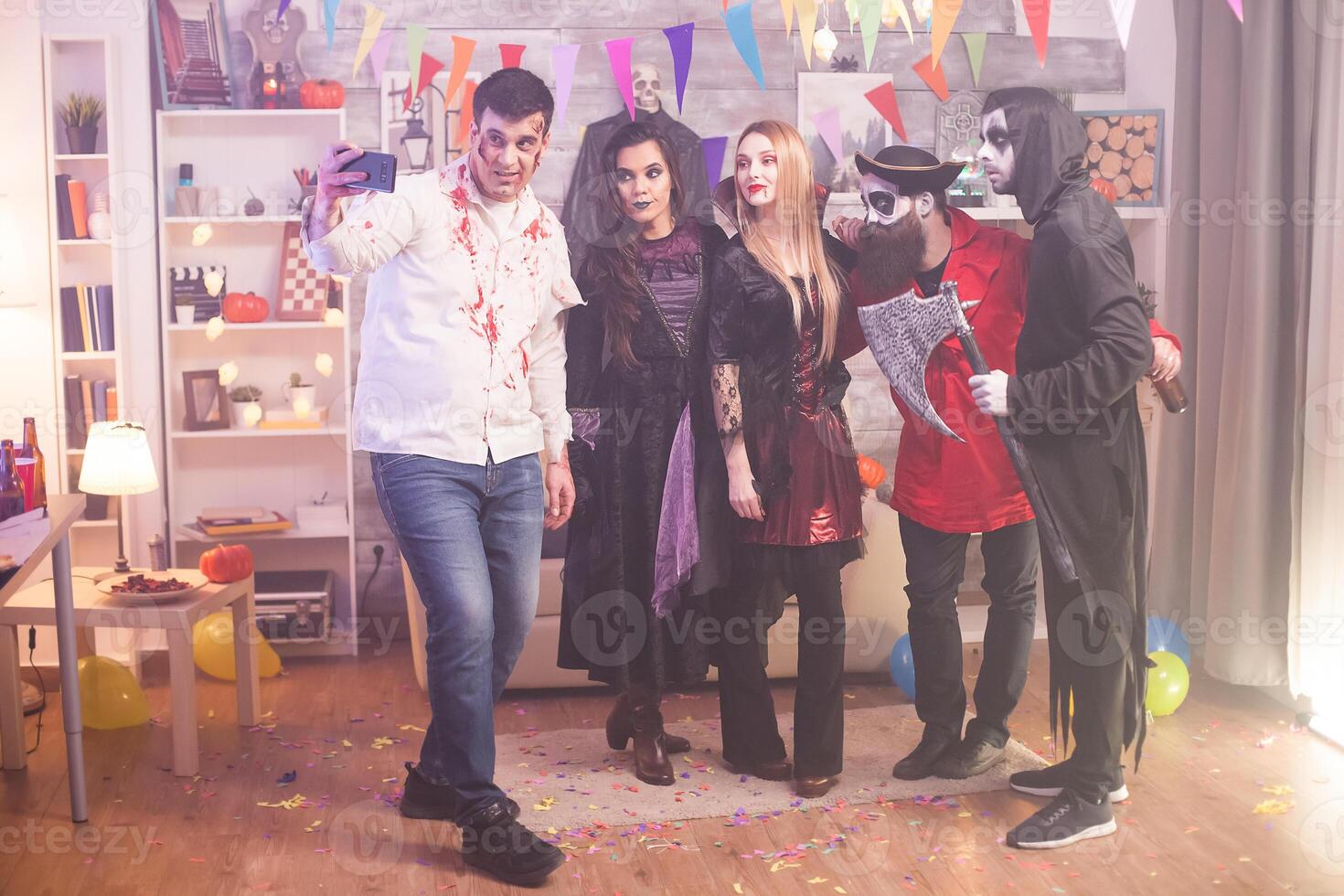 Group of friends looking into the camera and taking a selfie at halloween party in their costumes. photo