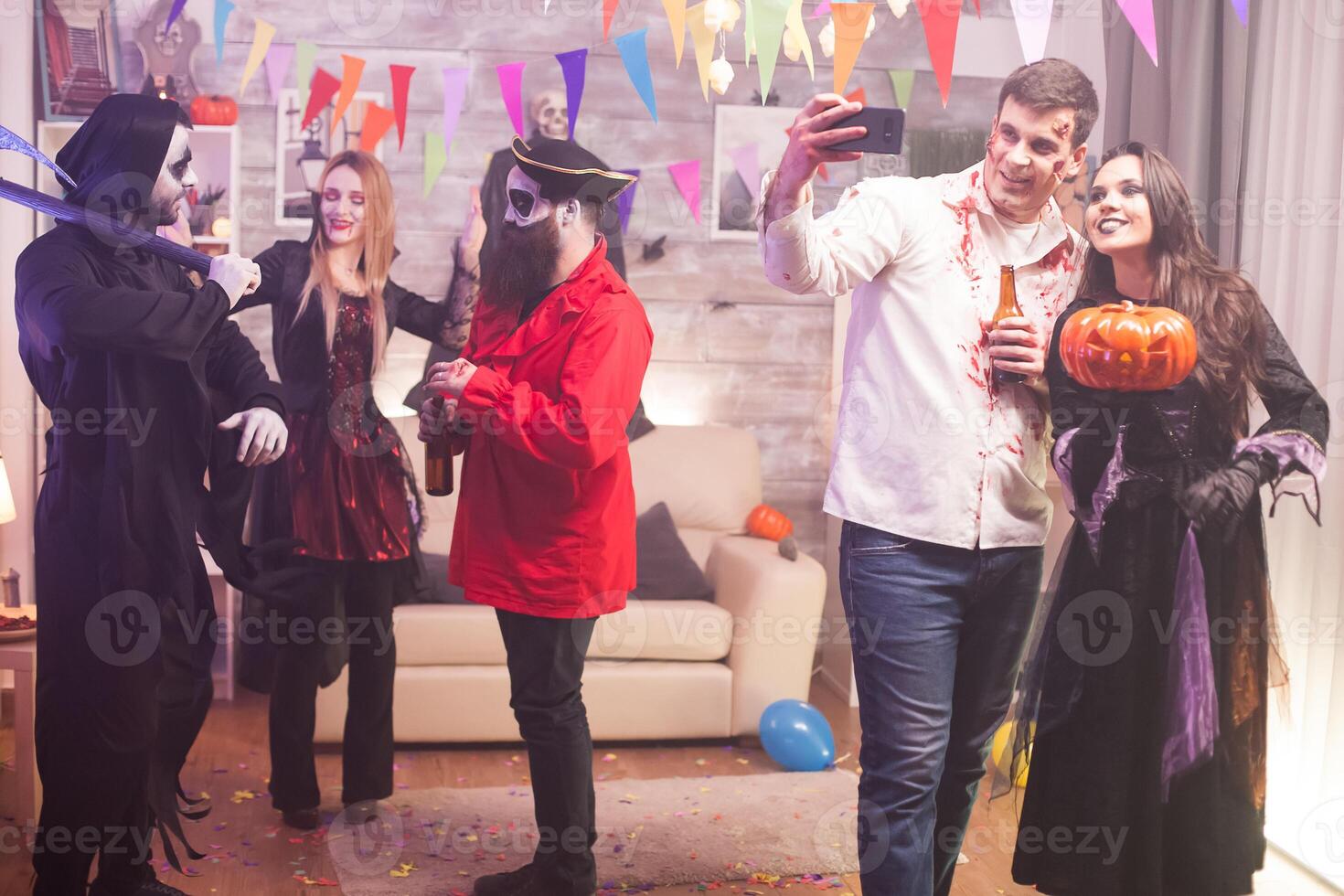 Smiling zombie and witch taking a selfie while celebrating halloween. photo