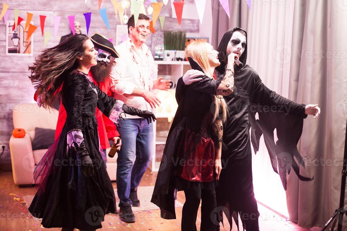Vampire woman and grim reaper doing karaoke while celebrating halloween. photo