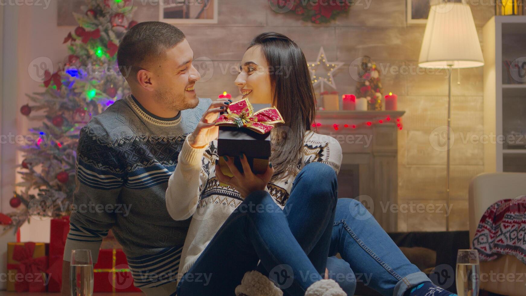 Young man surprising his girlfriend on christmas day with a surprise gift. Champagne glasses. photo