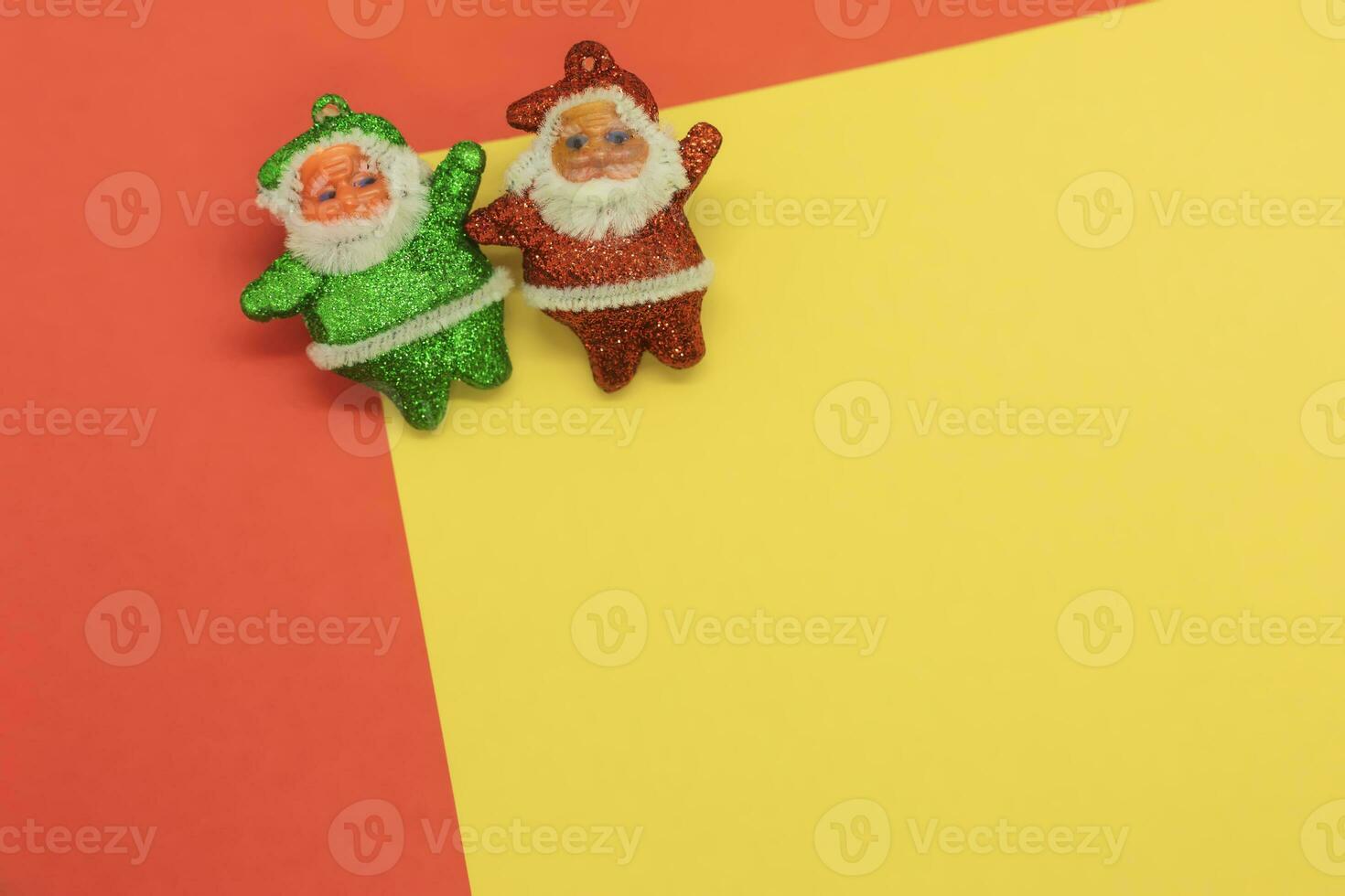 Two Santa Clauses and Christmas Elf on yellow and red background with copy space photo