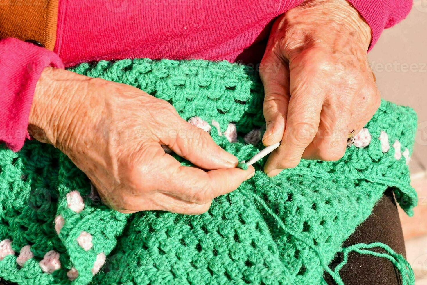 an older woman is knitting a green crocheted bag photo