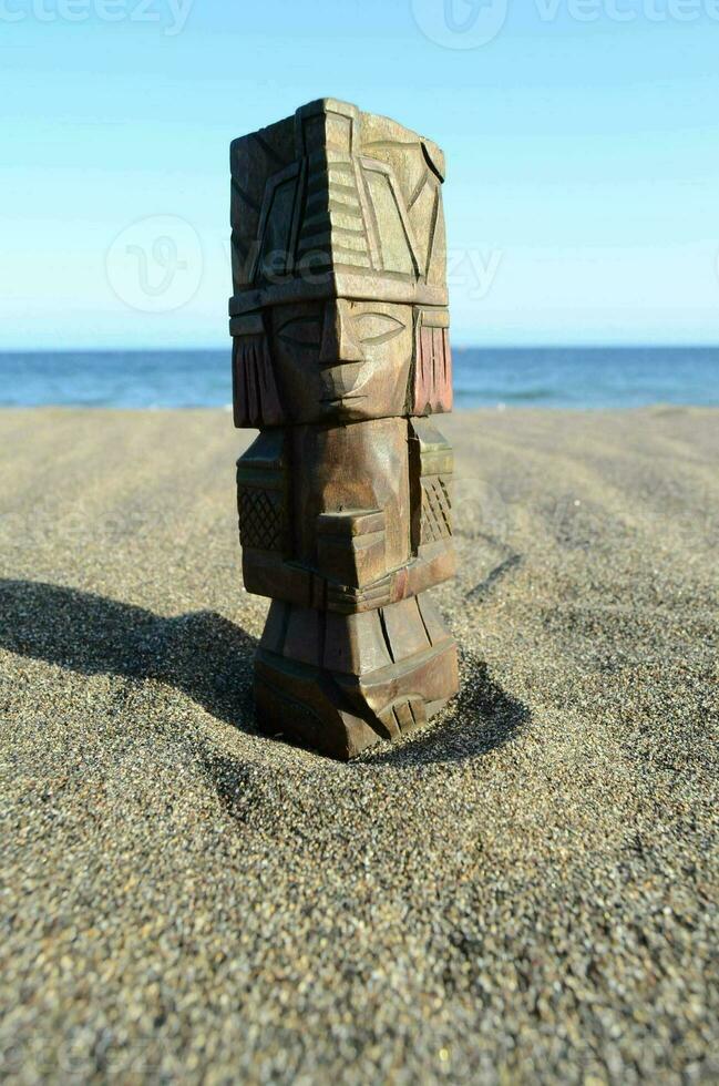 a wooden tiki statue on the beach photo