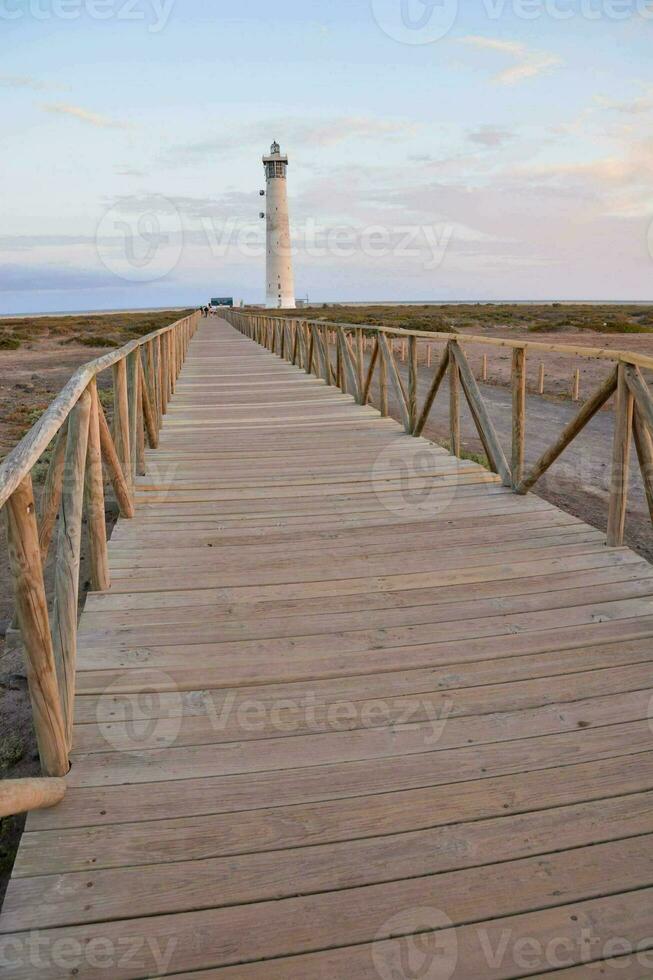 a wooden walkway leads to a lighthouse photo