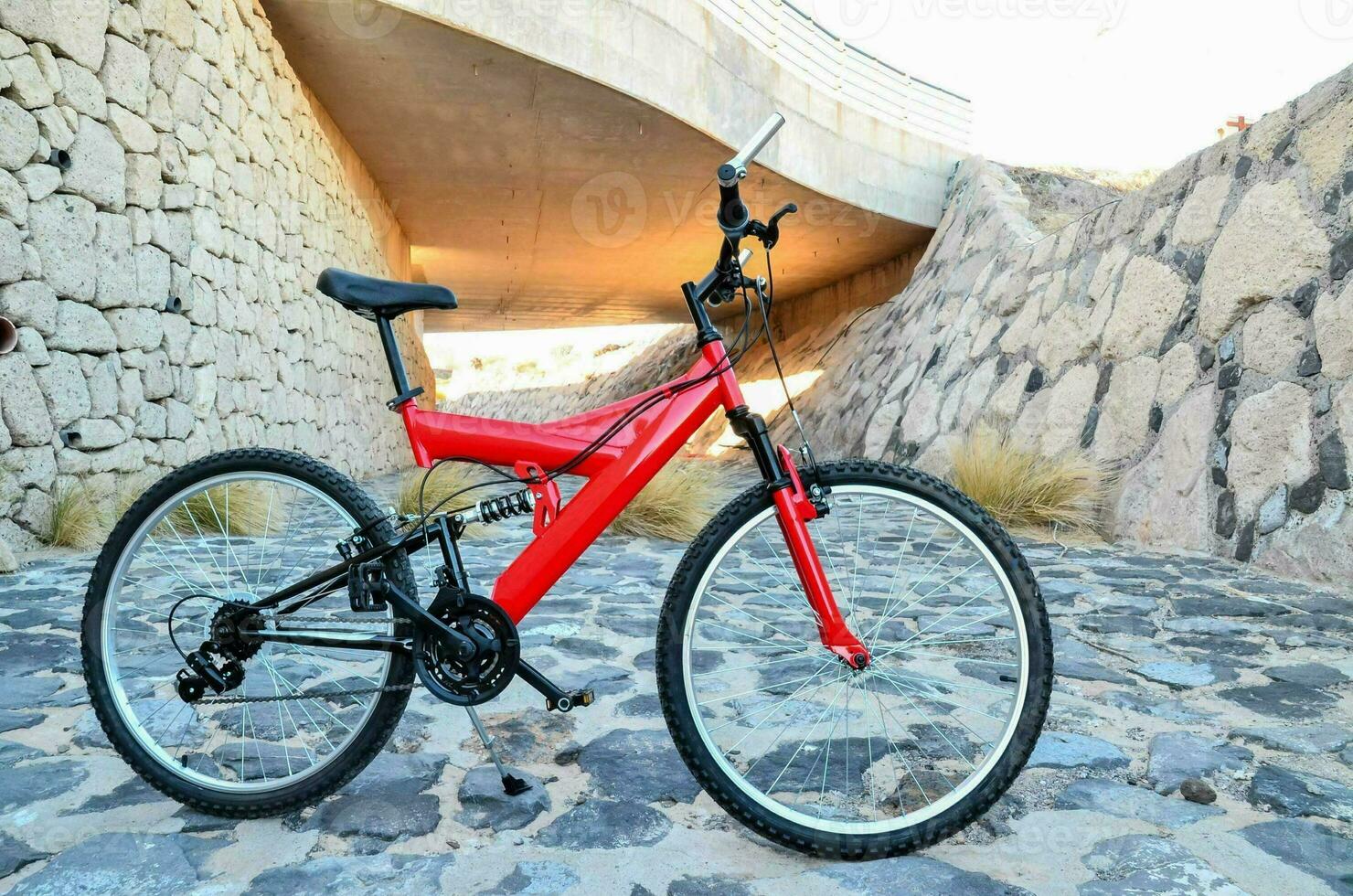 un rojo montaña bicicleta estacionado en un Roca camino foto