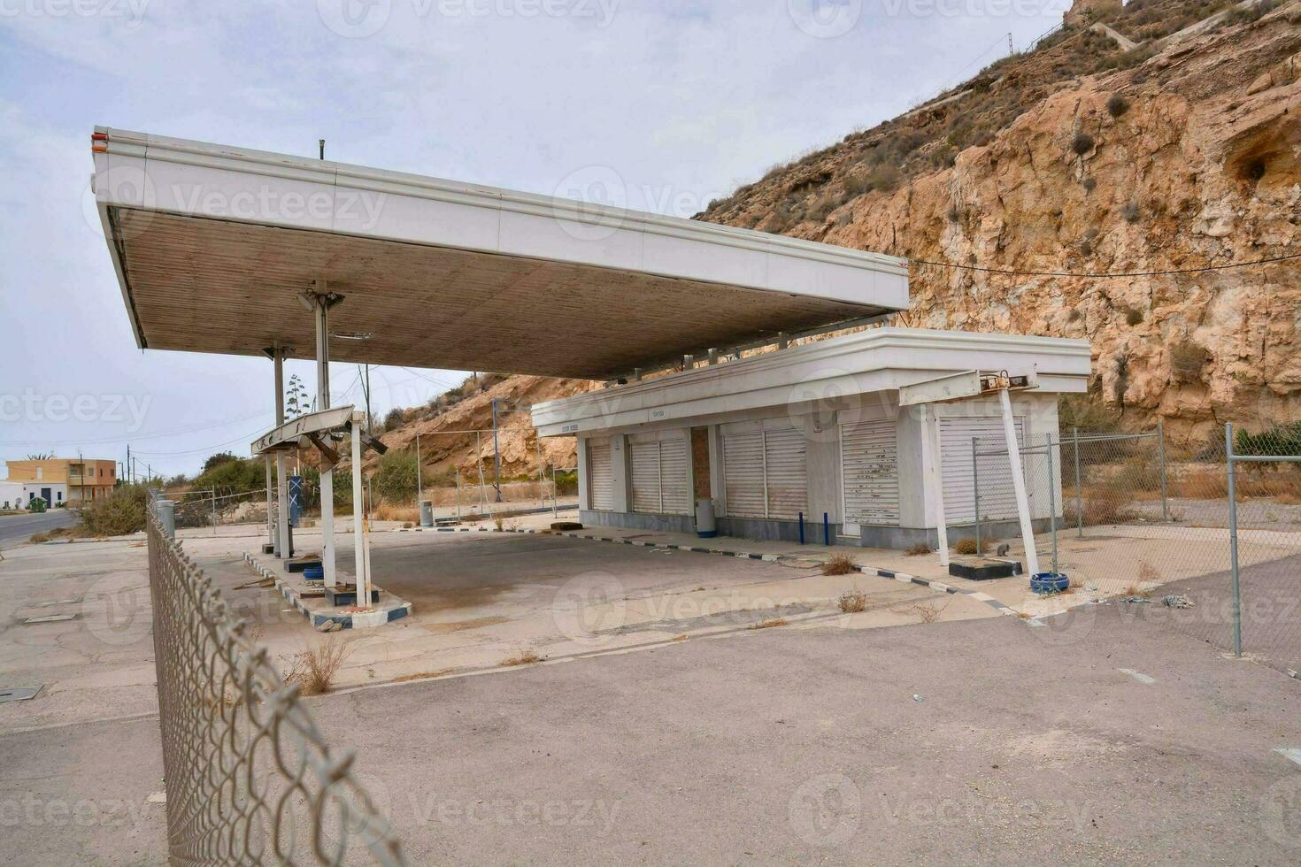 an empty gas station against a mountain photo