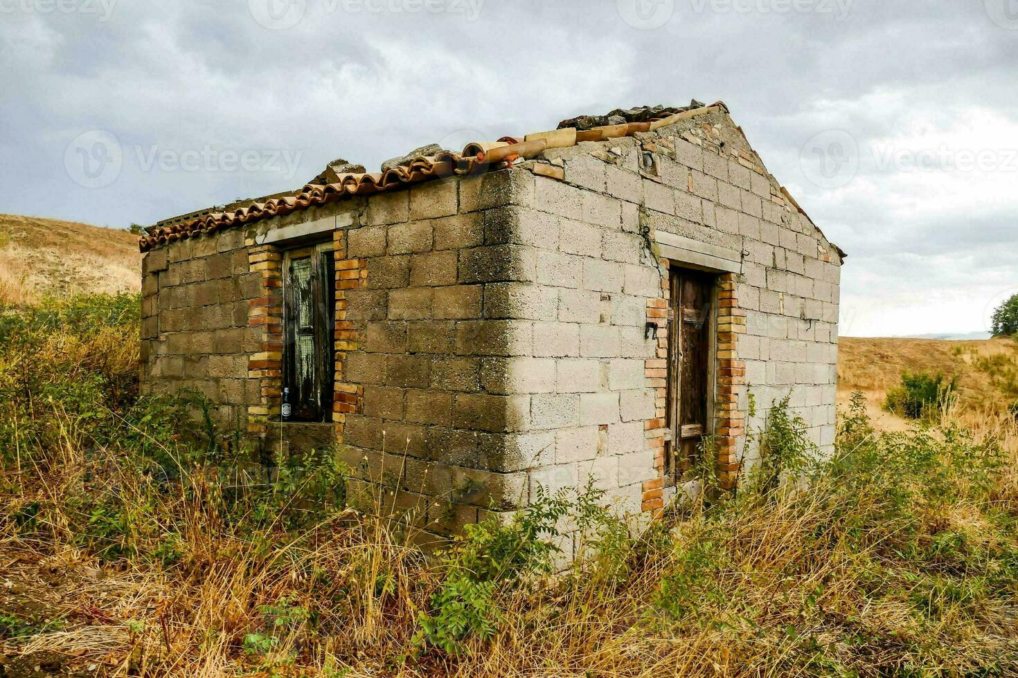 an old brick building in the middle of a field photo