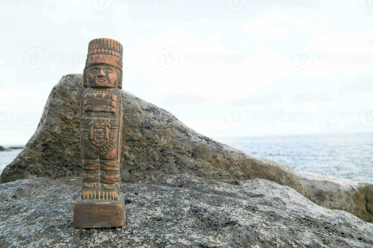 a wooden figure sitting on top of a rock photo
