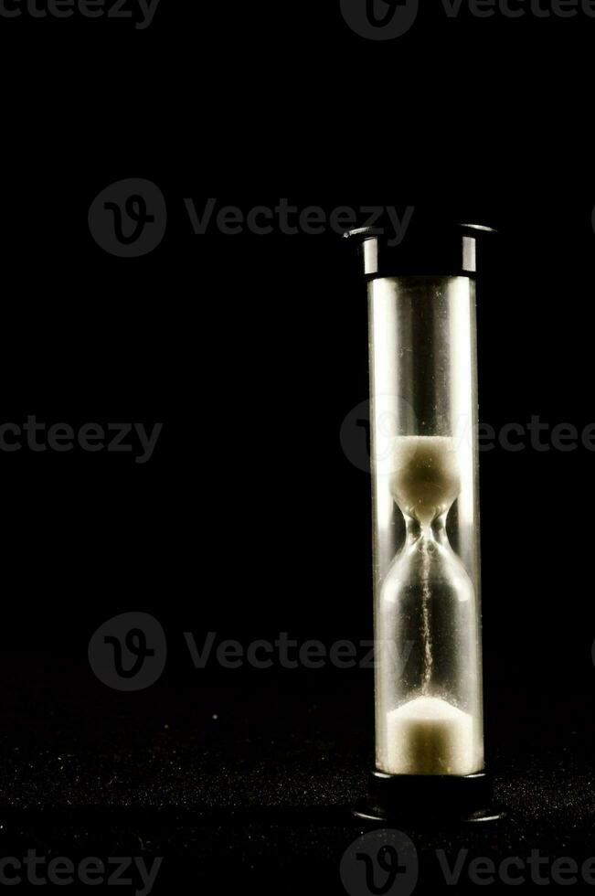 an hourglass with sand inside on a black background photo