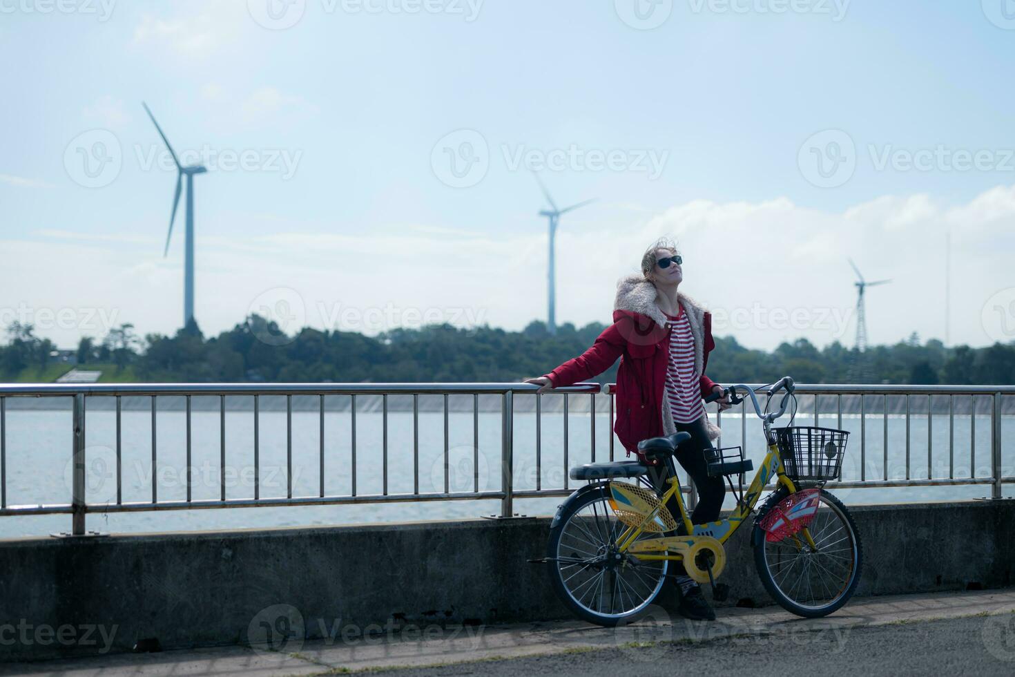 Young woman walks with a bicycle on the road along the dam that produces electricity. To exercise in the morning photo