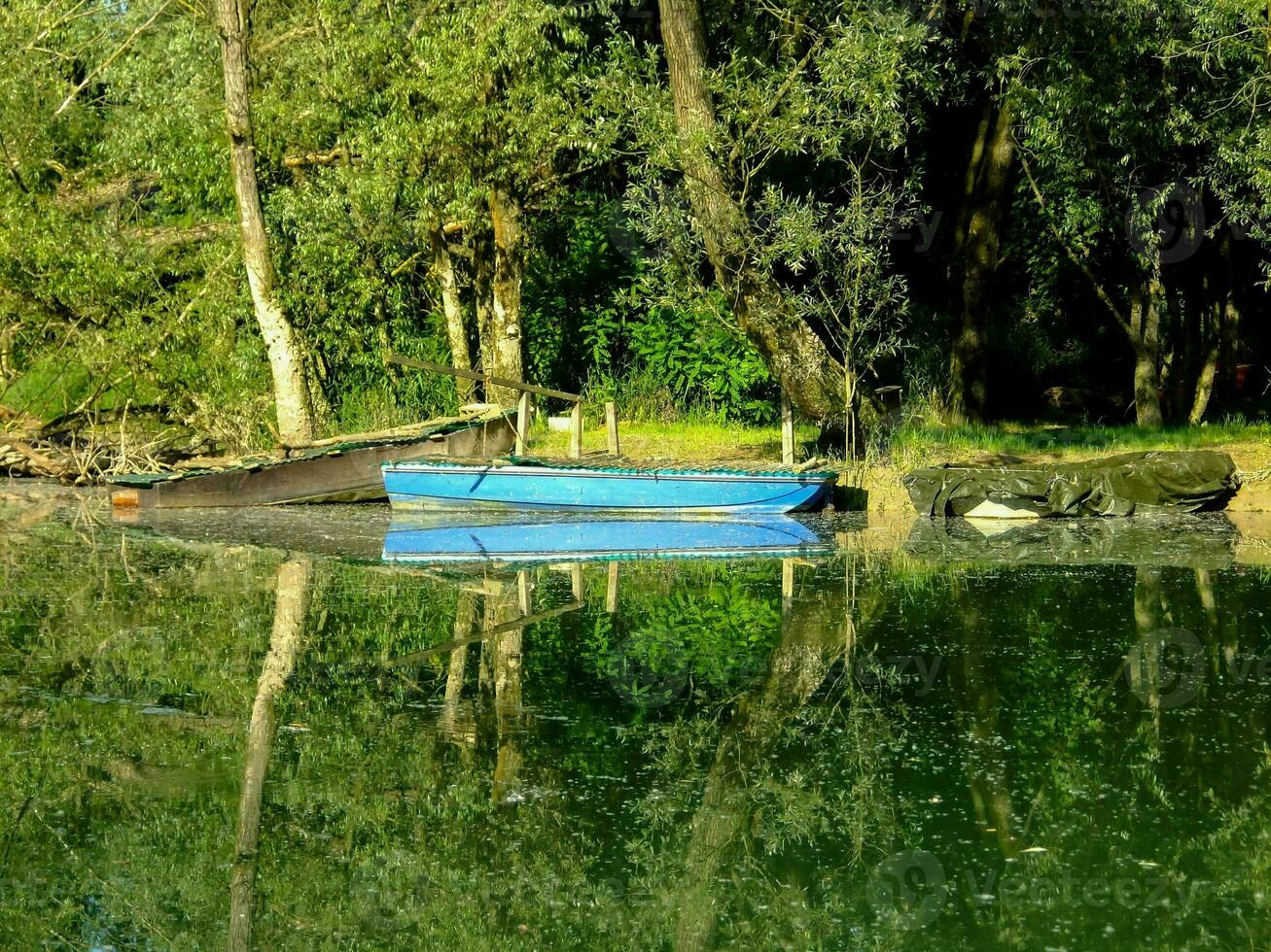 a blue boat is parked on the shore of a lake photo