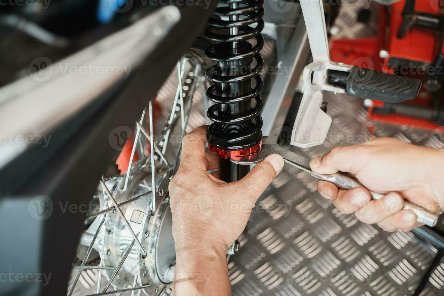 Motorcycle mechanic use spanner wrench to set the preload and locked the spring perches ,repair and maintenance motorcycle concept.selective focus photo