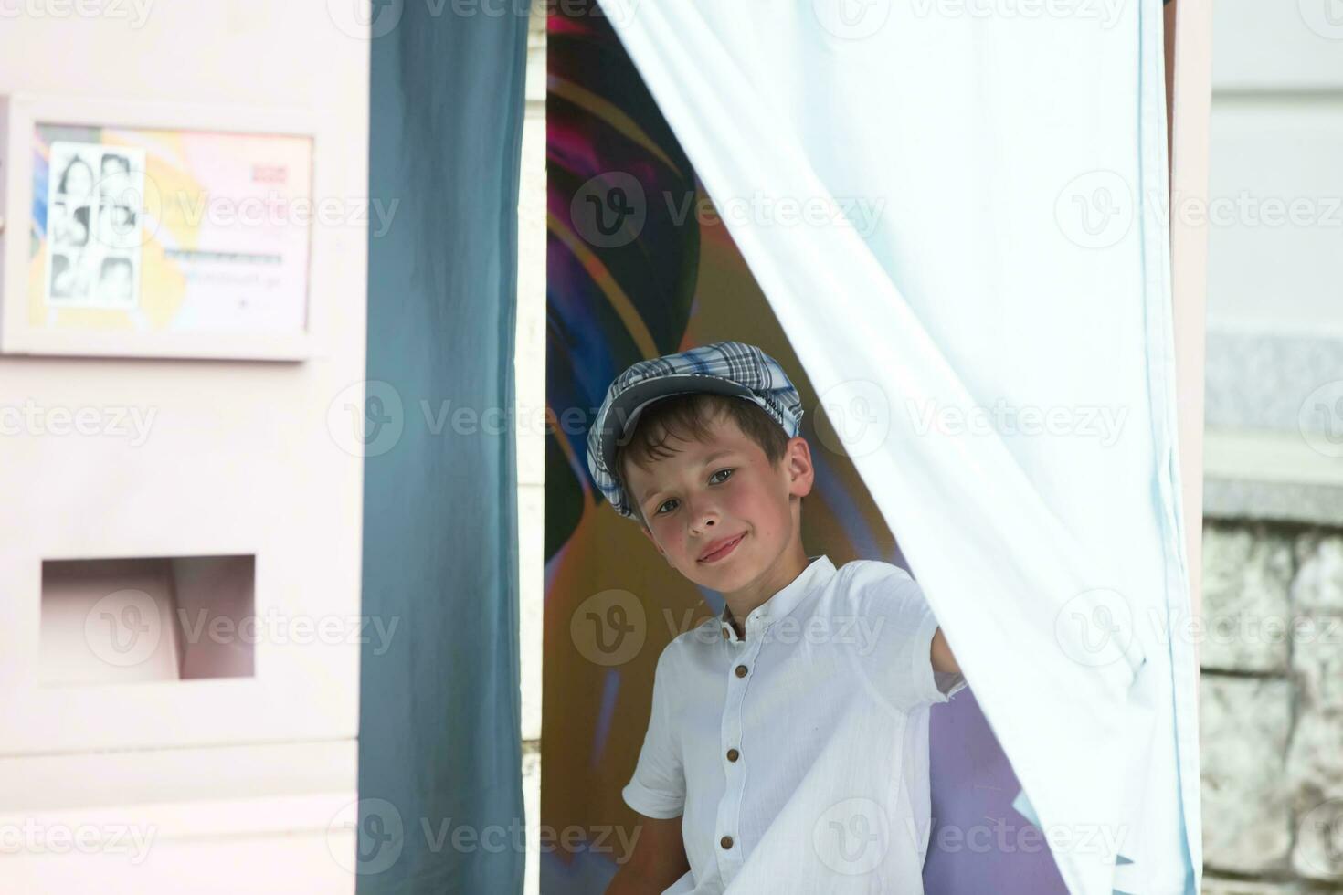 Cheerful boy looks out of the photo booth.