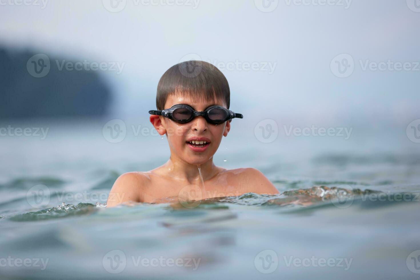 A boy in swimming goggles swims in the sea. photo