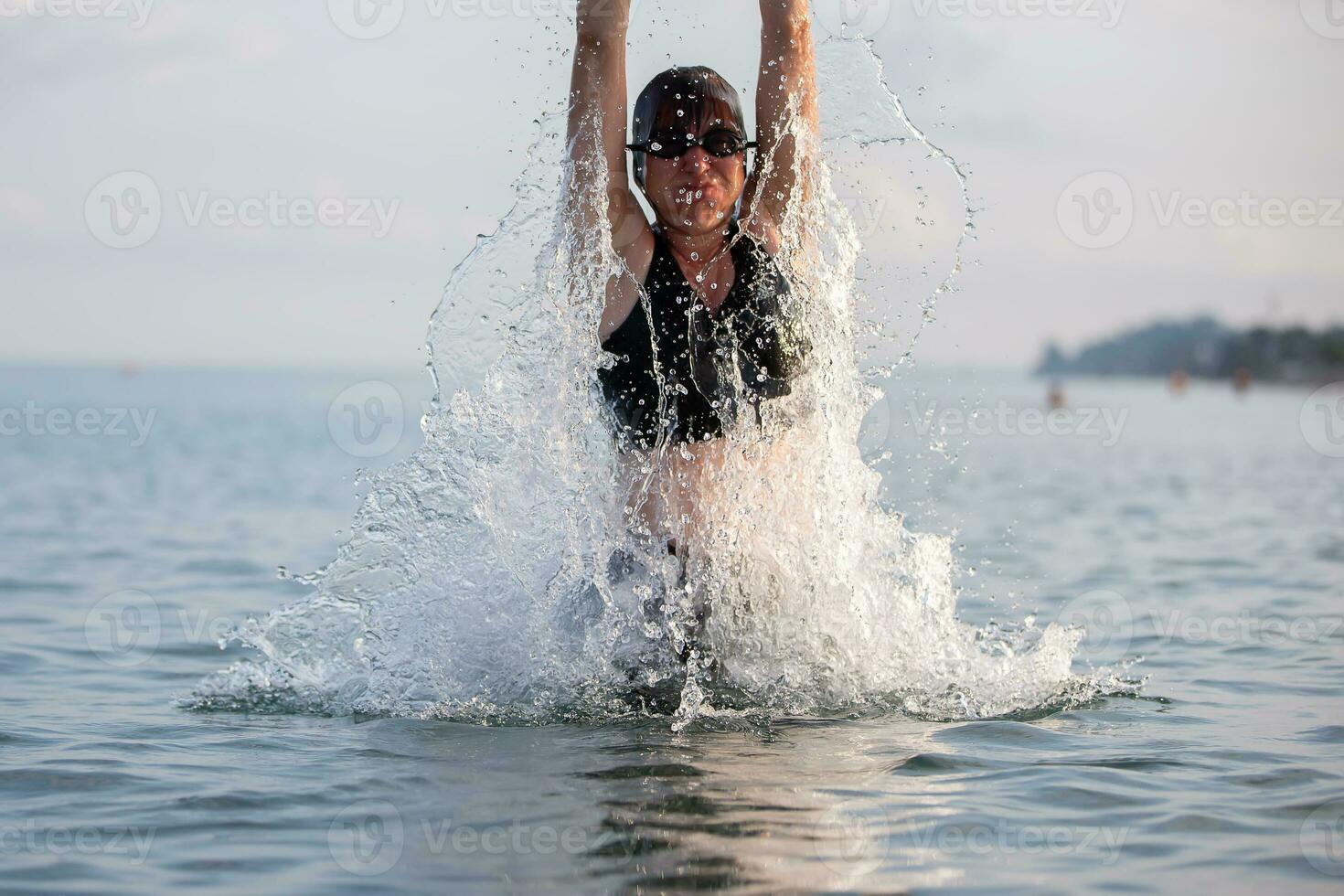 Woman swimmer jump out of sea water water with streaming splashes. photo