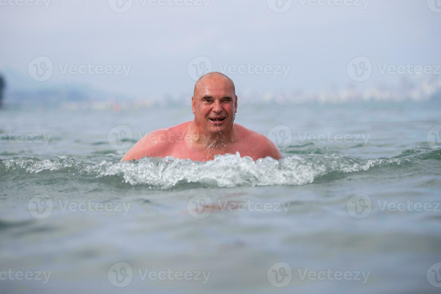 An elderly man bathes in sea water. photo