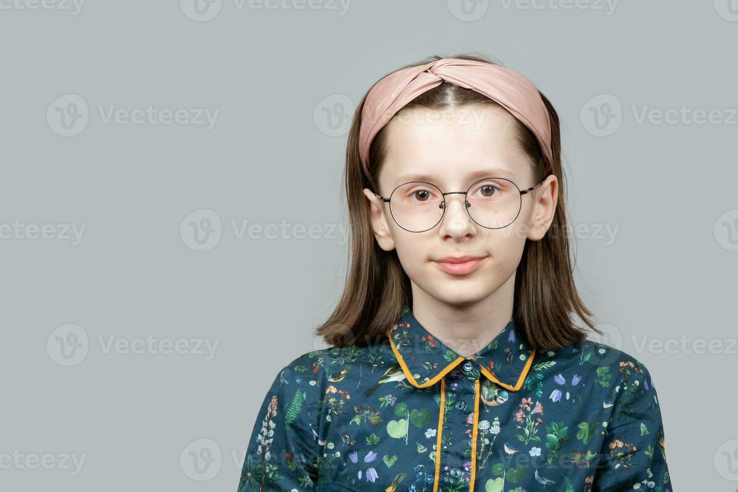 gracioso nerd niña en lentes mira inteligentemente dentro el cámara. foto