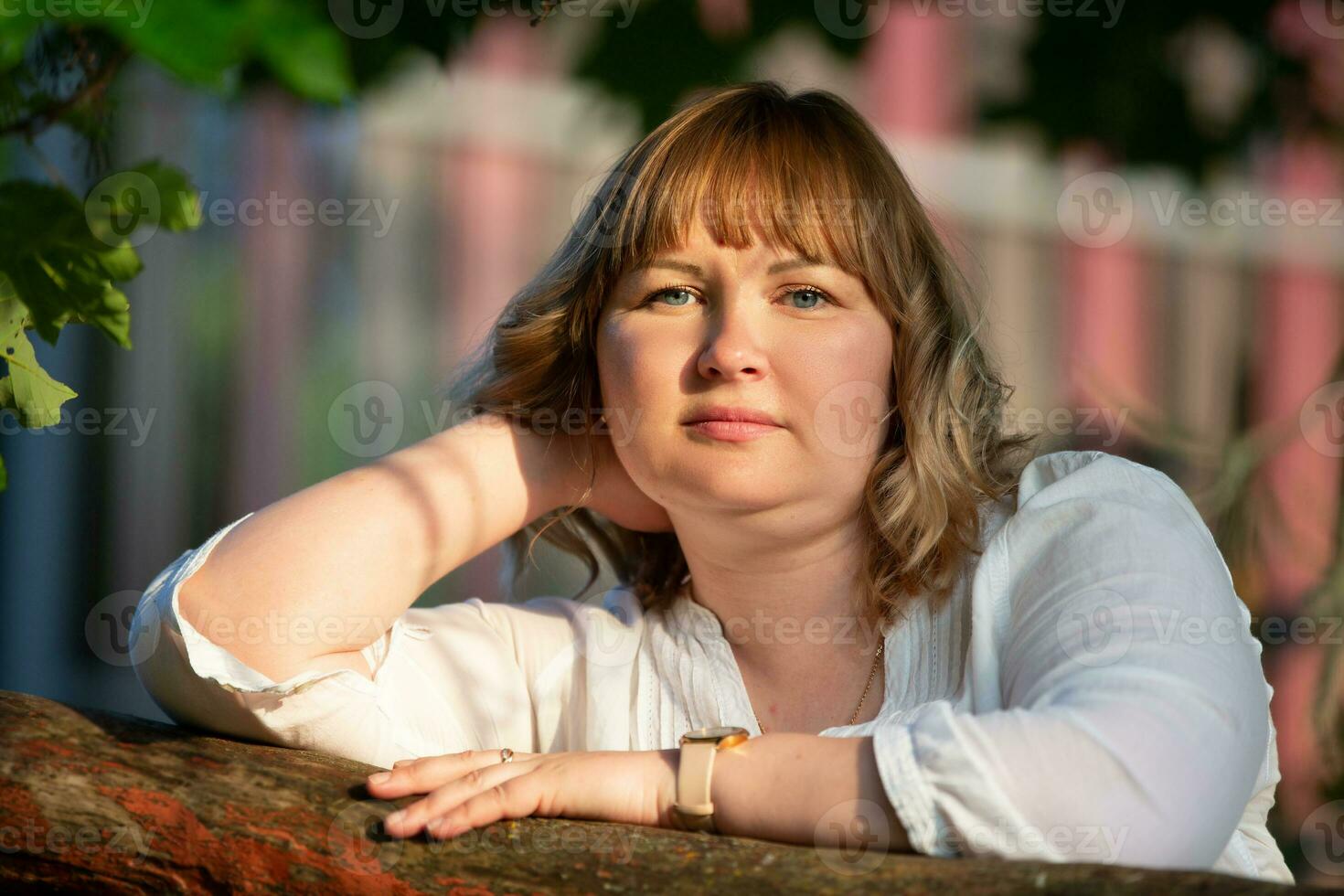 A beautiful blonde woman with a full face and blue eyes looks into the camera. photo