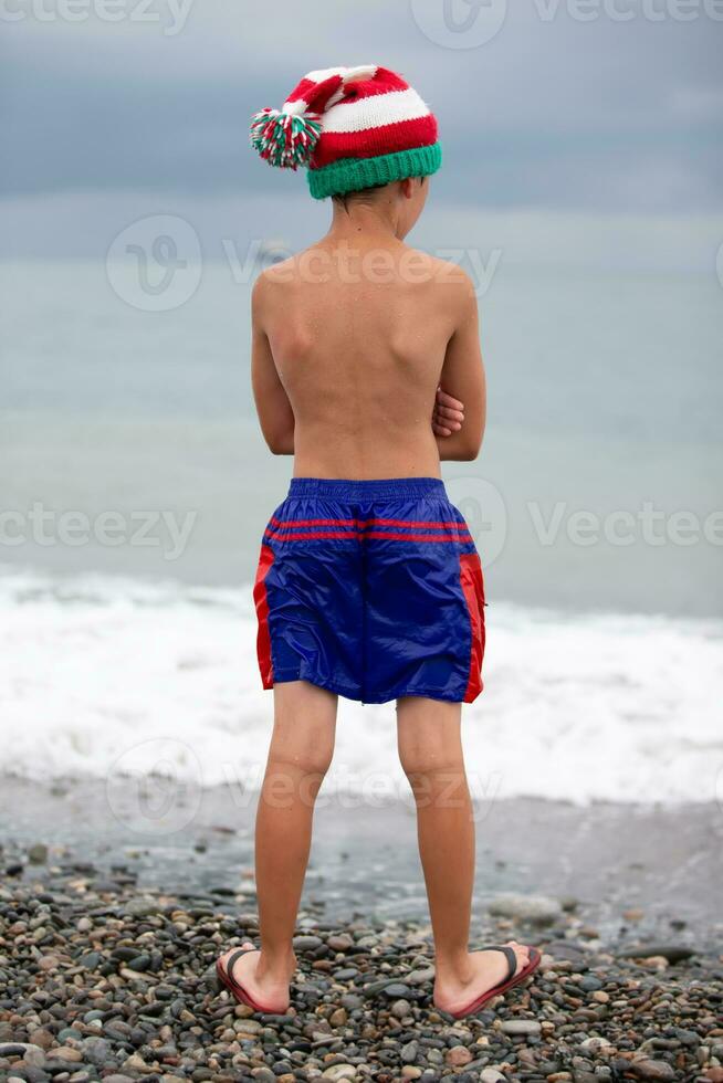 Boy in a Christmas hat on the seashore. Meeting Christmas in the southern countries. photo