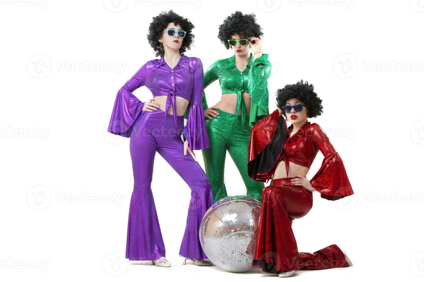 Three girls on a white background posing with a disco ball. Clothes from the seventies or eighties for a disco party. photo