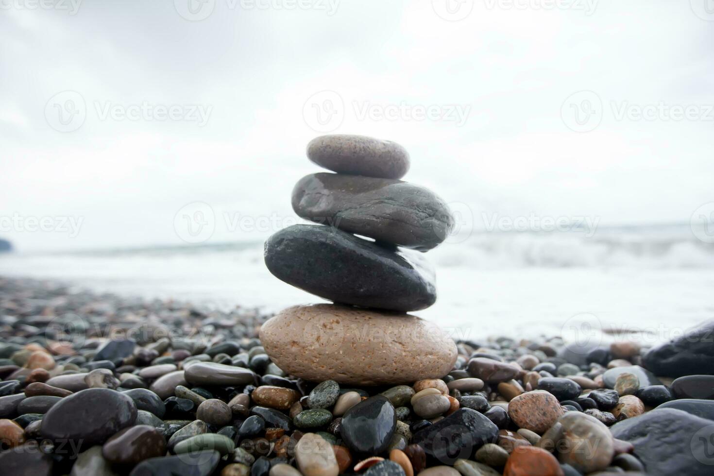 Sea stones are stacked on top of each other against the backdrop of the sea. Pebble beach. photo