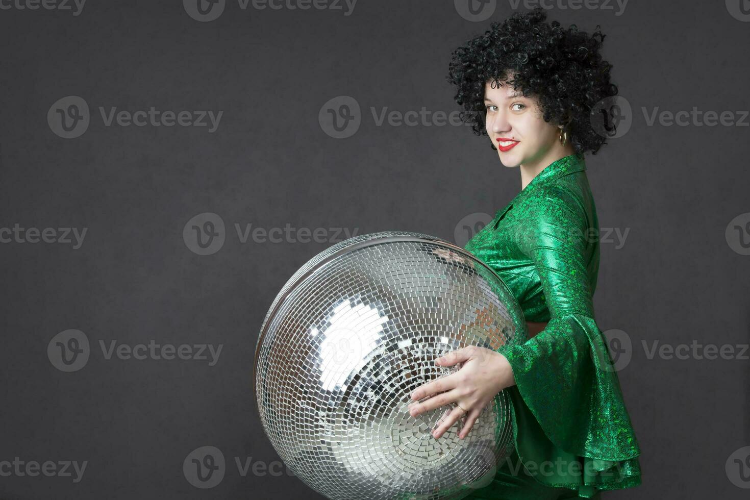 Beautiful girl holding a disco ball on a gray background. Disco style. photo