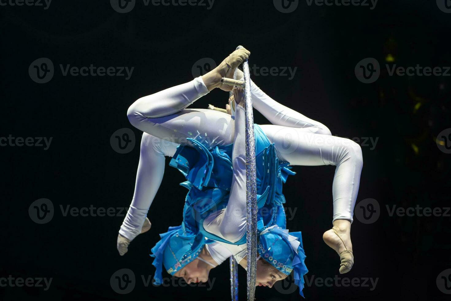 Two acrobat girls show a circus number on a dark background. Acrobatic performance. photo