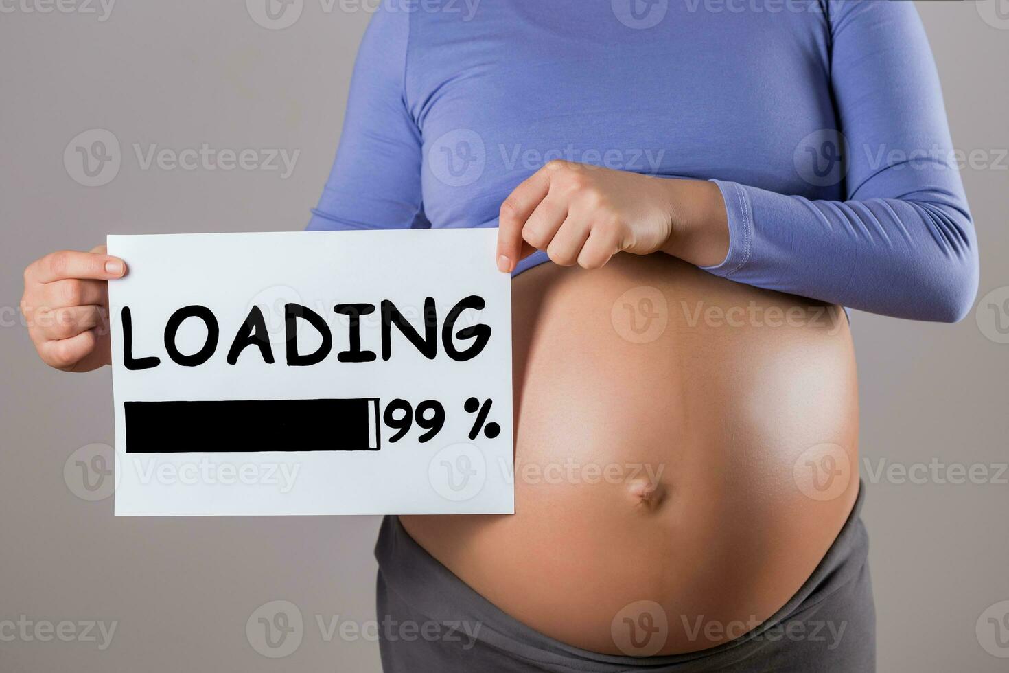 Image of close up stomach of pregnant woman holding paper with text loading on gray background. photo