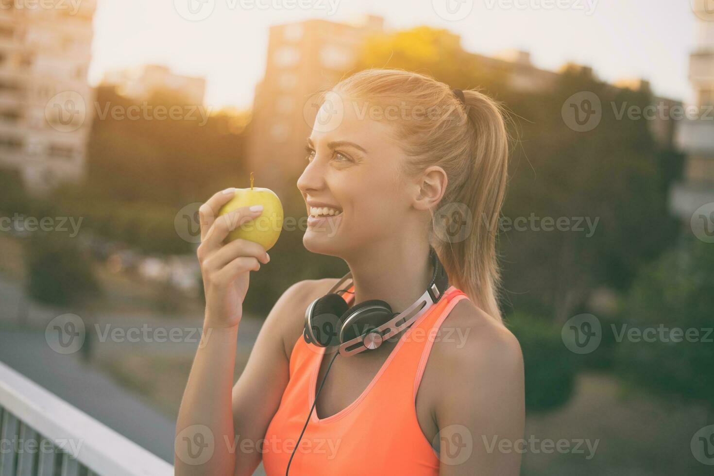 Beautiful sporty woman eating apple while resting from exercise.Toned image. photo