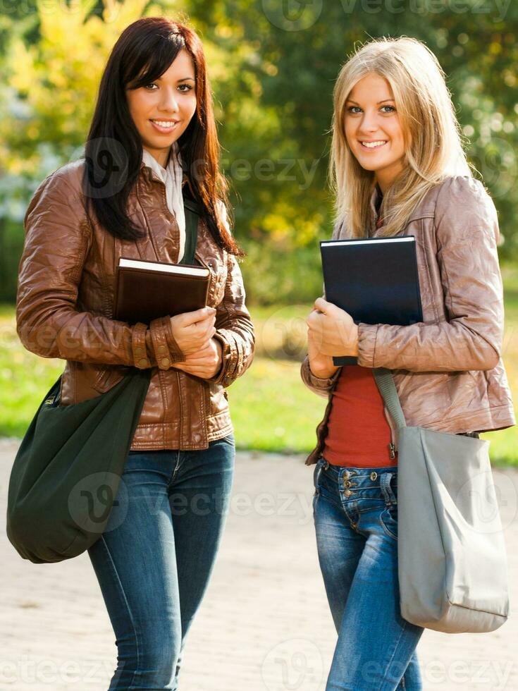 dos joven estudiante muchachas con libros en el parque foto
