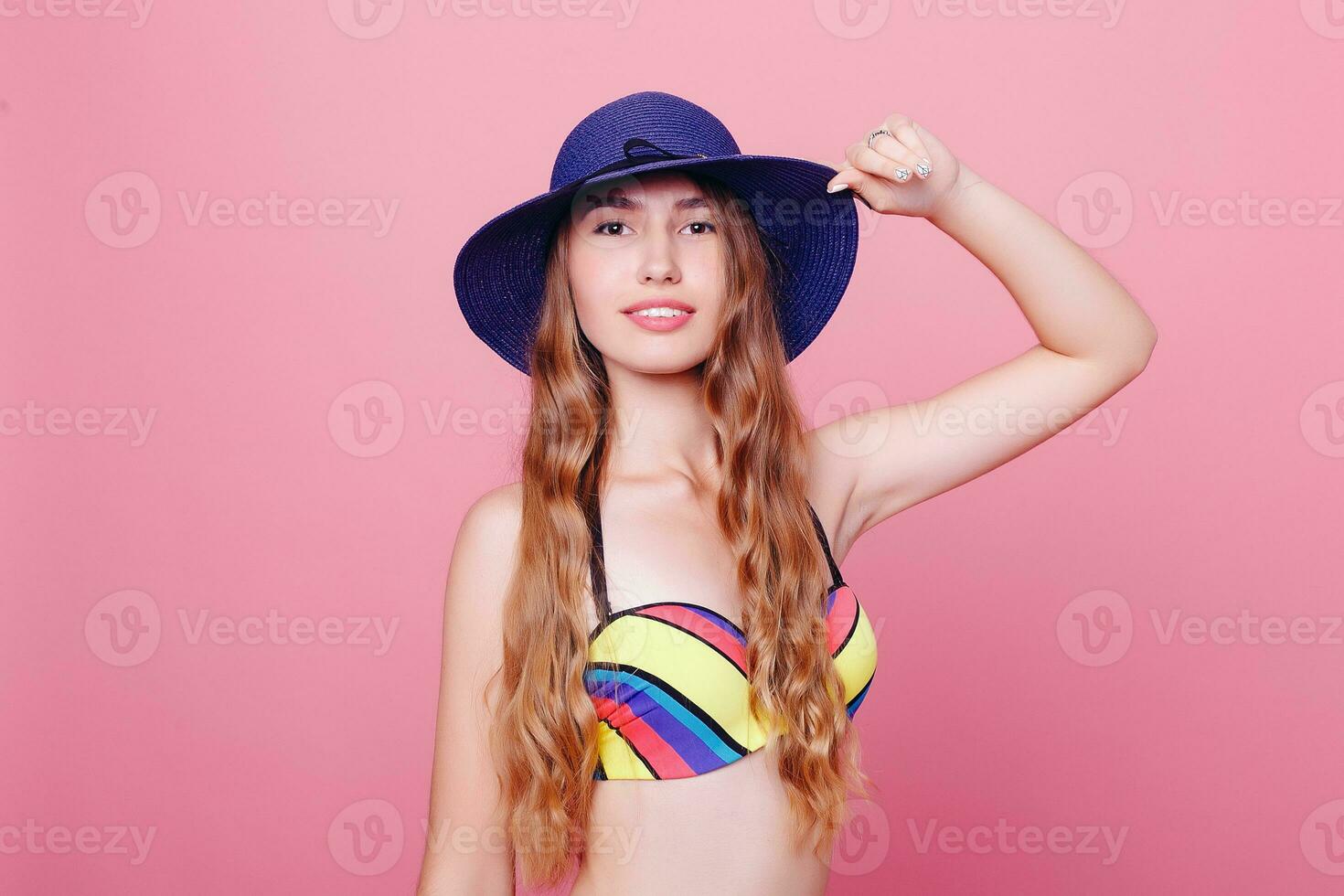 Adorable brunette in bikini posing on pink background photo