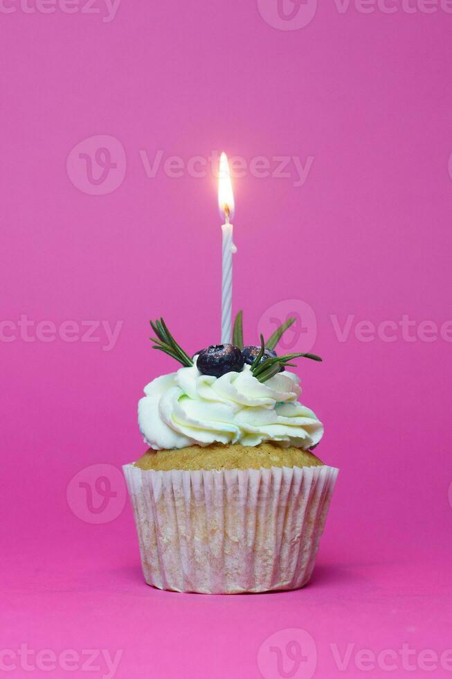 birthday cupcake with one burning candles over pink background photo