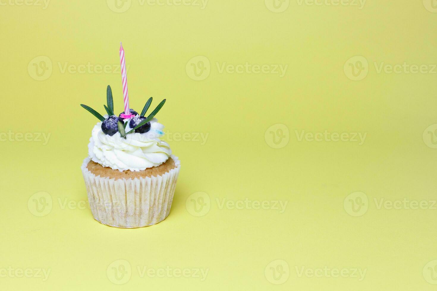 birthday cupcake with one burning candles over yellow background photo